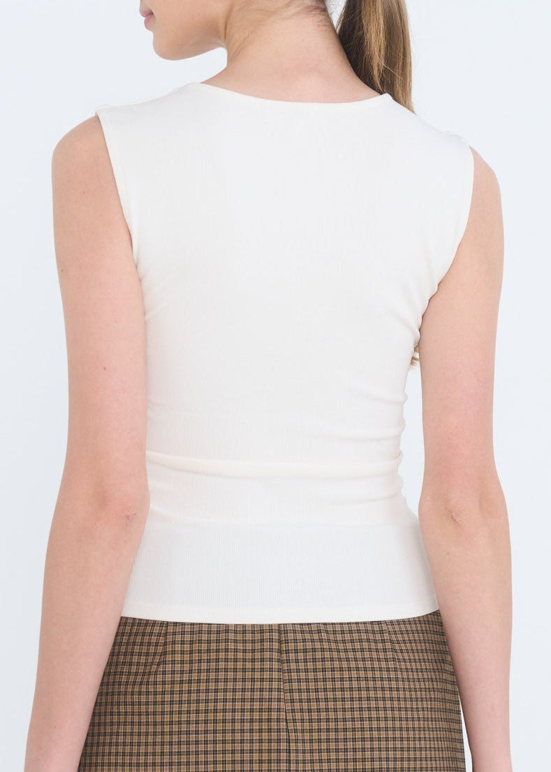 Woman wearing a white sleeveless top and plaid skirt on a white background