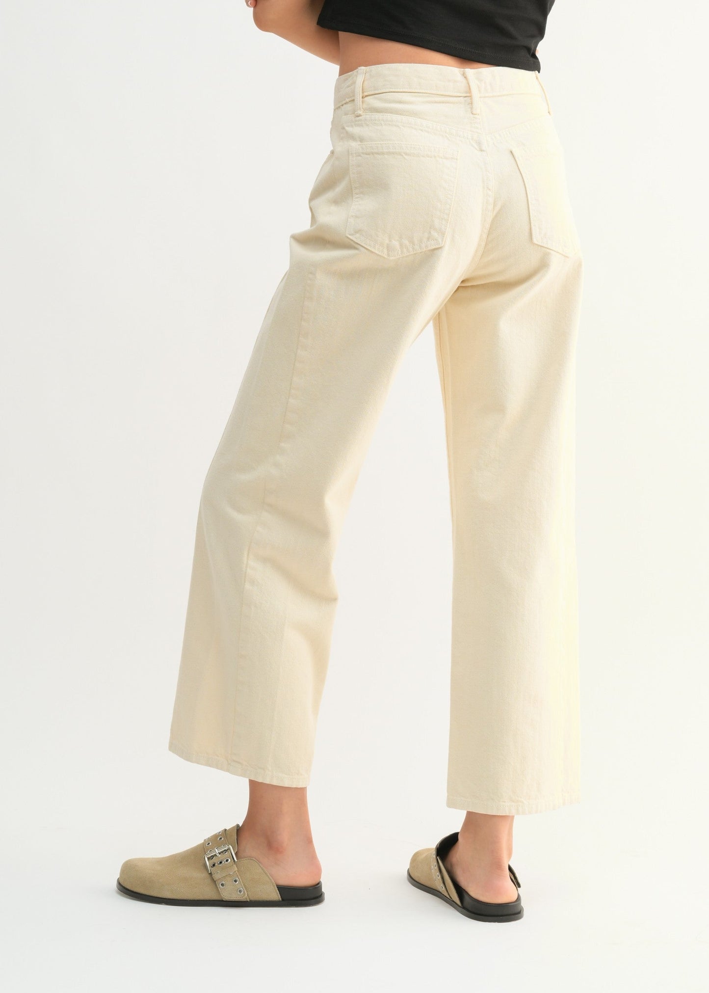 Woman wearing a black crop top with text and beige pants on a white background