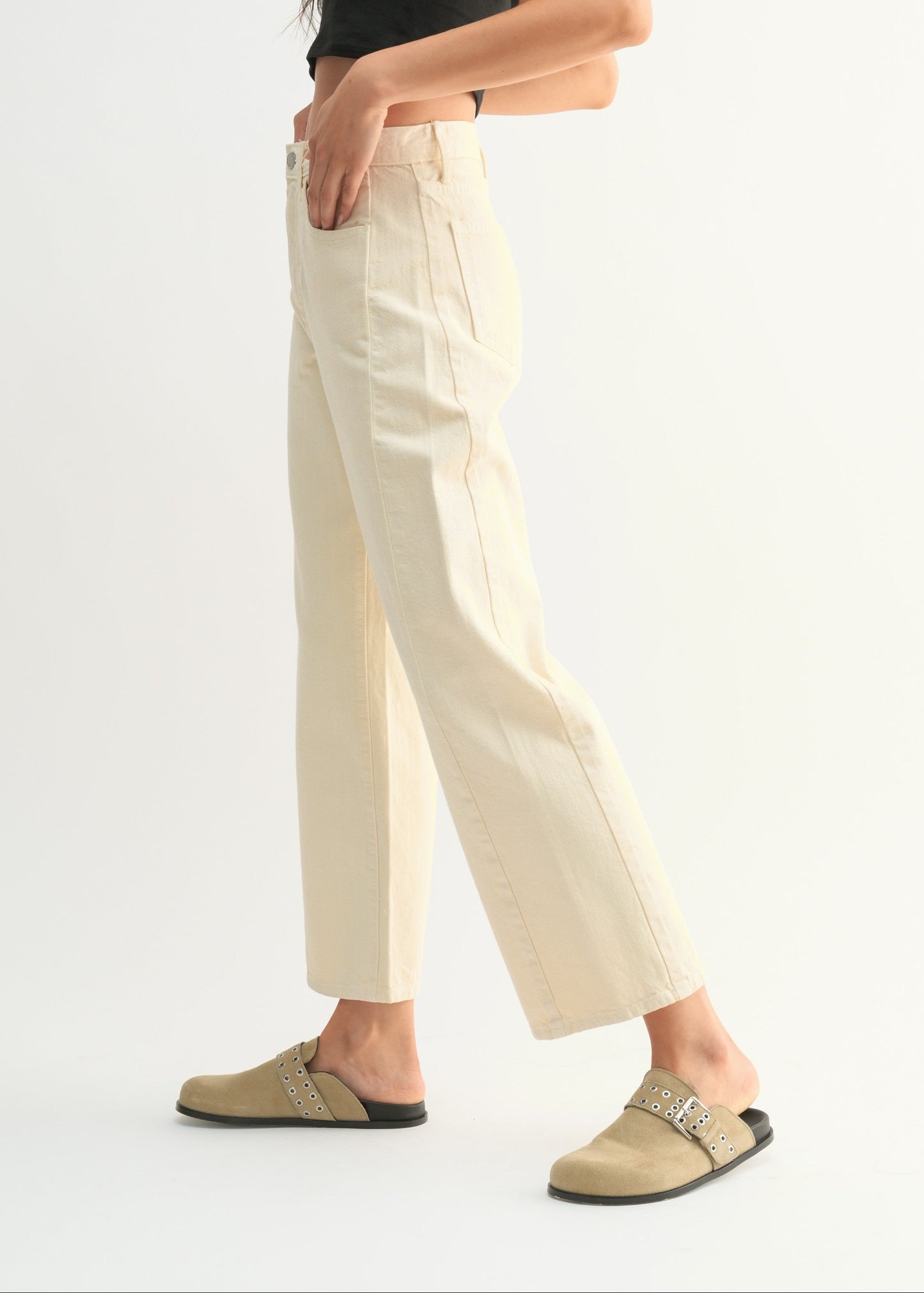 Woman wearing a black top and white pants on a white background