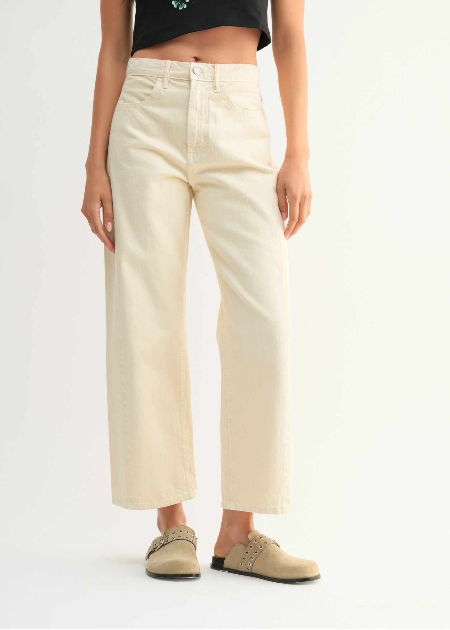 Person wearing cream-colored pants and a black top with butterfly design on a white background