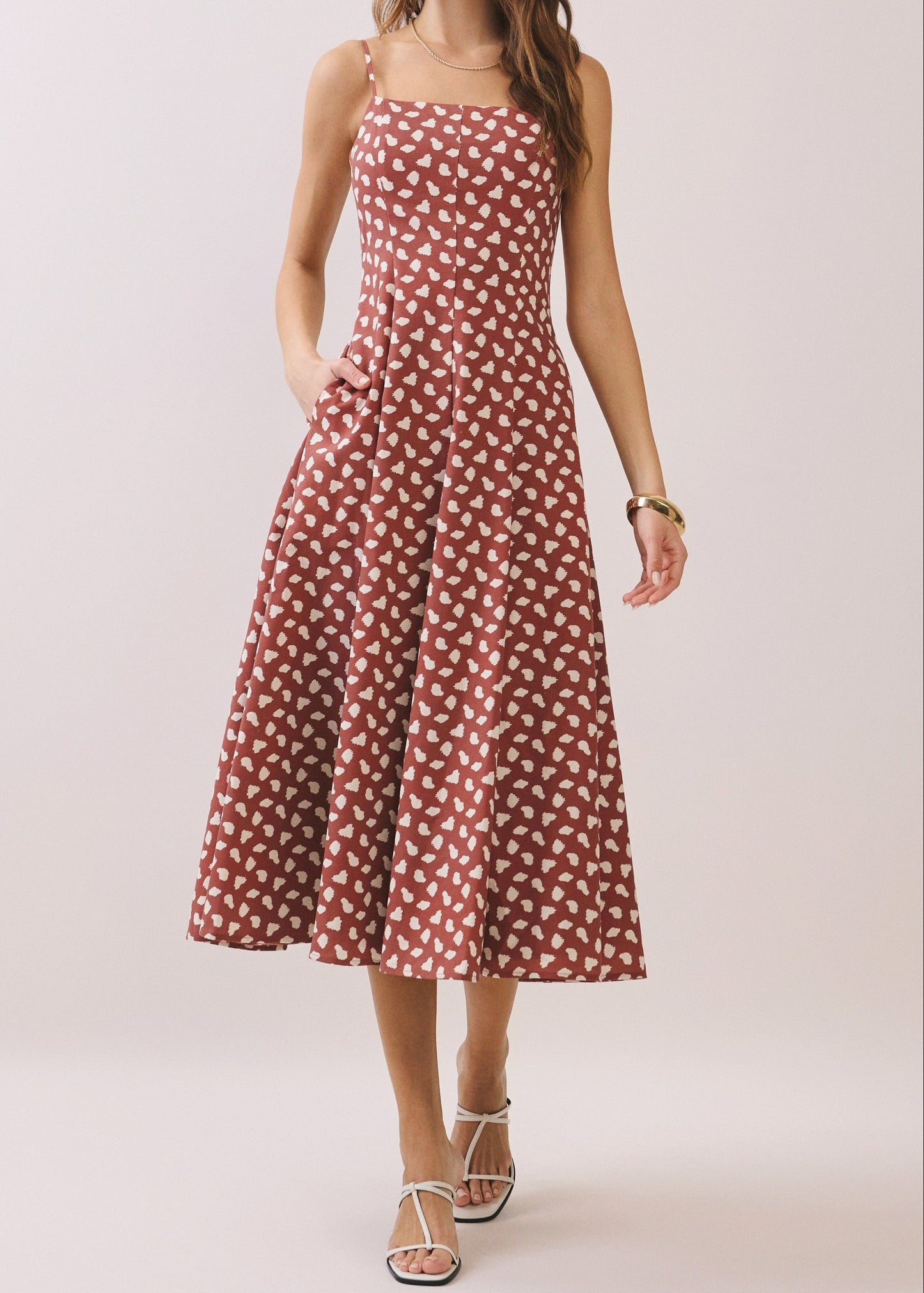 Woman wearing a BROWN and white patterned dress on a plain background