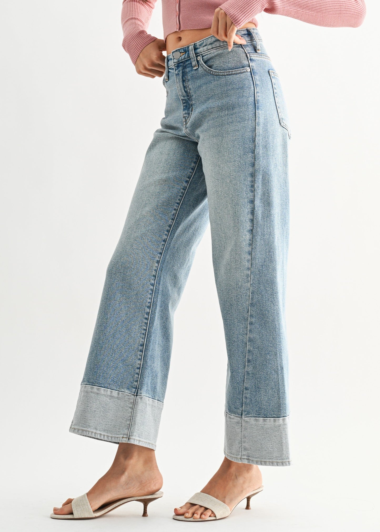 Woman wearing a pink top and blue jeans on a white background