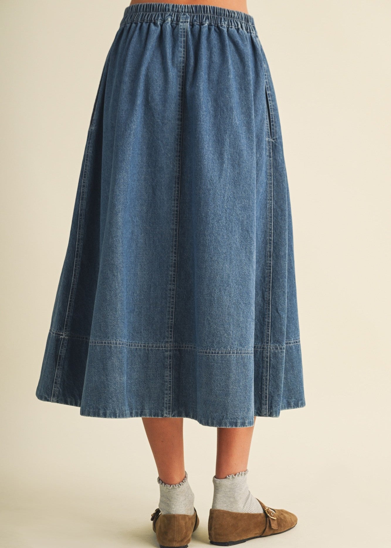 Blue denim skirt worn by a person on a beige background