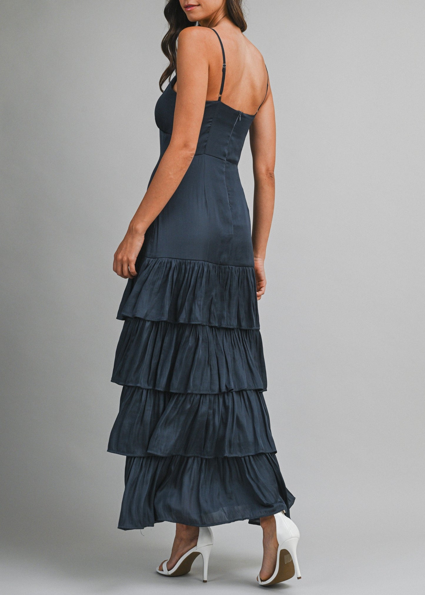 Woman wearing a dark blue tiered dress on a gray background