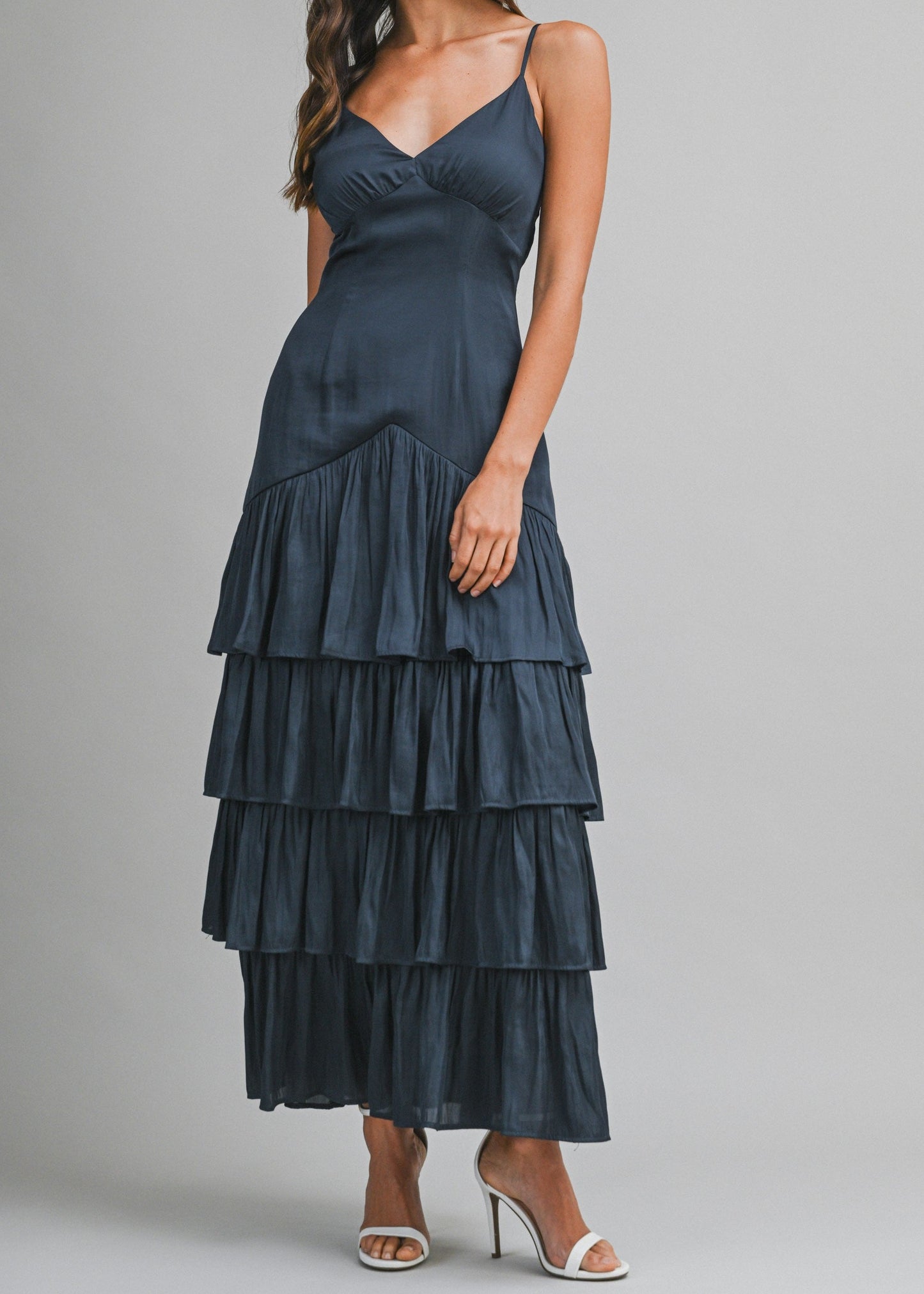 Woman wearing a dark blue tiered dress on a gray background