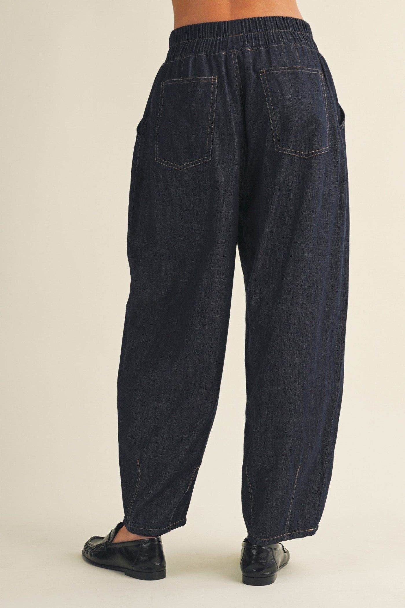Dark blue denim pants on a beige background