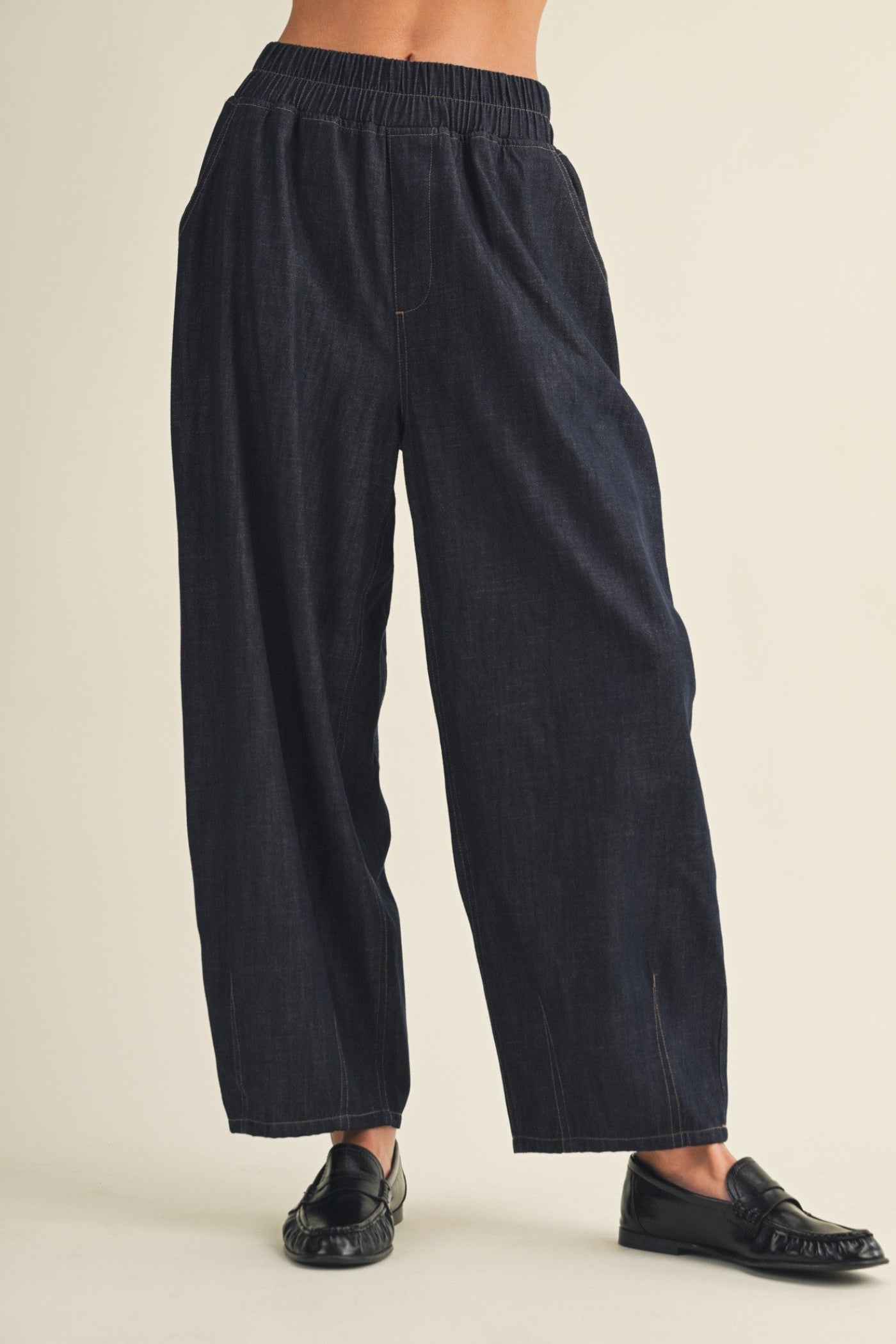 Black wide-leg pants worn by a person on a beige background