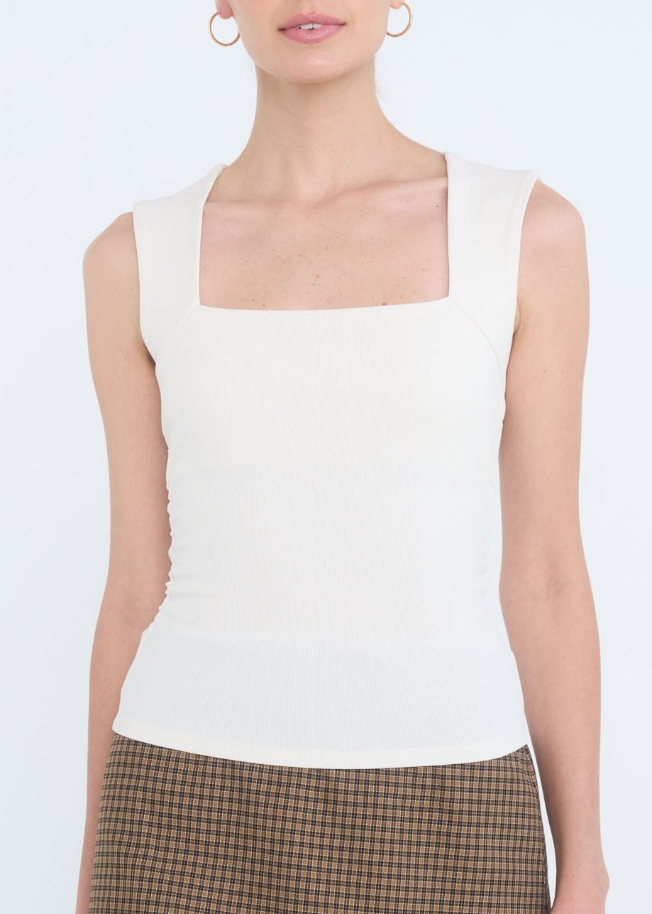 Woman wearing a white sleeveless top and brown checkered skirt on a white background