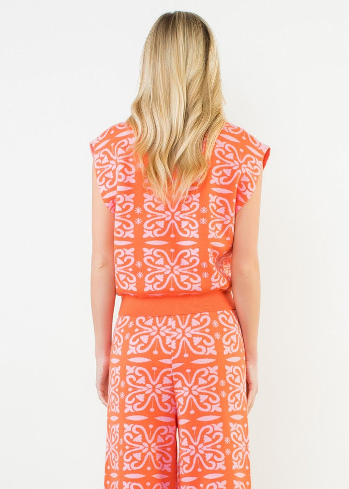 Woman wearing an orange and white patterned dress against a white background